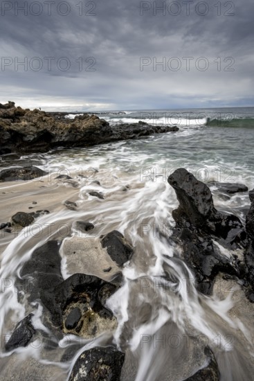 Waves blaze on the beach, rocky coast with volcanic stones, long exposure, Playa de la Pequeña, Punta Usaje, Lanzarote, Canary Islands, Spain