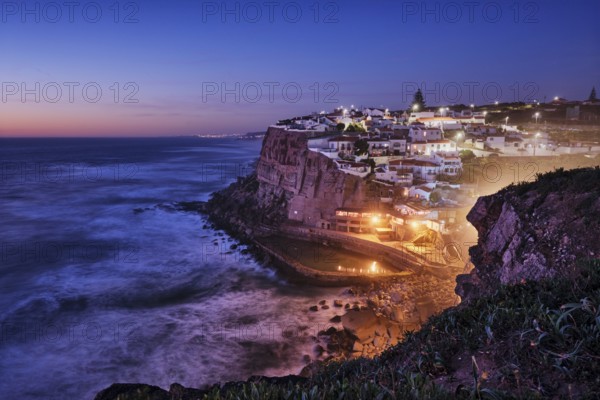 Scenic view of the seaside Azenhas do Mar fishing village on cliff on Atlantic ocean coast, Portugal in evening twilight dusk