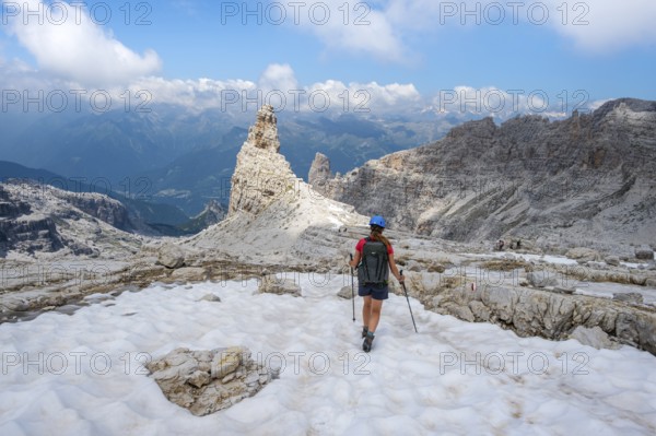 Female hiker on hiking trail 305 crossing a snowfield, Brenta Mountains, Parco Naturale Brenta-Adamello, Trentino, Italy