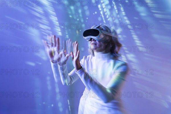 An elderly Asian woman engages with the metaverse using a virtual reality headset. She extends her hands to interact with digital elements, showcasing technology's role in modern life
