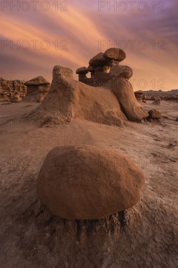 Dramatic sandstone formations under a vibrant sunset sky in Goblin Valley State Park, Utah, USA. Erosion shapes the landscape into unique, surreal figures
