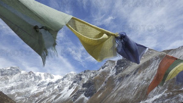 Various prayer flags flutter against snow-capped mountains in the background, trekking at Annapurna Circuit, Manang, Nepal