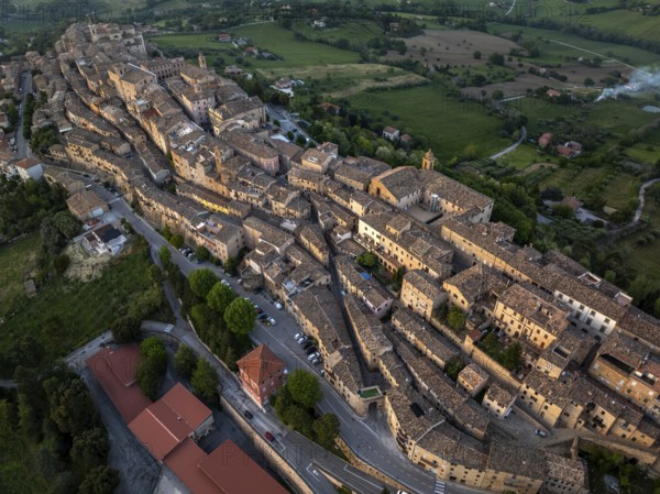 Aerial view of Treia, Italy, highlighting its remarkable medieval architecture nestled amid lush fields. This panorama captures the unique layout of the historic town