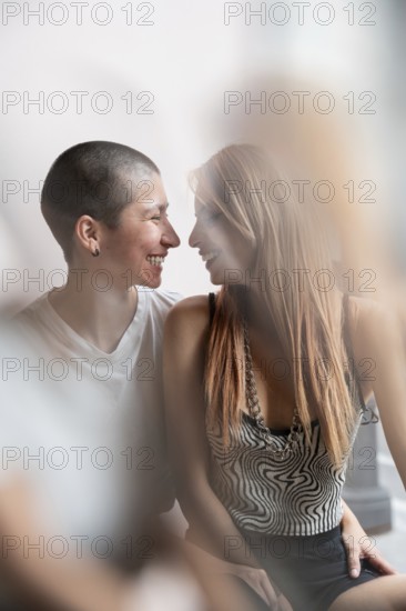 A loving lesbian couple shares an intimate moment, embracing warmly and gazing into each other's eyes, creating a tender and heartfelt atmosphere