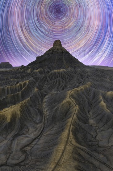 Stunning night view of the Milky way over Utah sandstone desert, showcasing star trails in a clear sky. The rugged terrain adds to the majestic landscape beauty