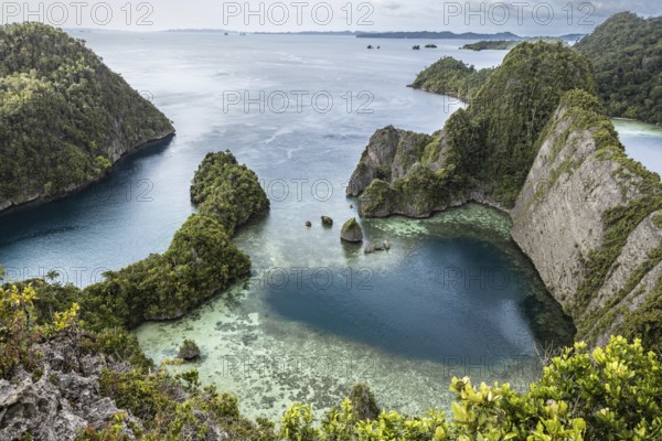 From above, this drone-captured image showcases the breathtaking Raja Ampat Archipelago in Indonesia. Lush green islands surrounded by turquoise waters highlight the unique topography and vibrant marine environments of this stunning location