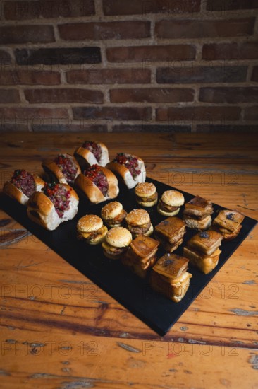 A selection of gourmet sliders and assorted bites arranged on a wooden table. The image captures an inviting presentation ideal for showcasing culinary art