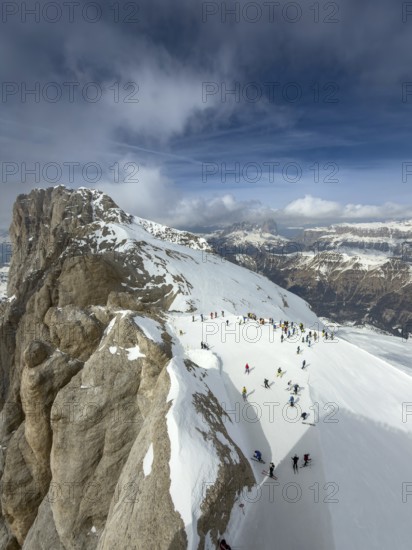 View of the snow-covered Marmolta (3343 m) with skiers in the foreground and clouds in the background, Trentino, Dolomites, Italy