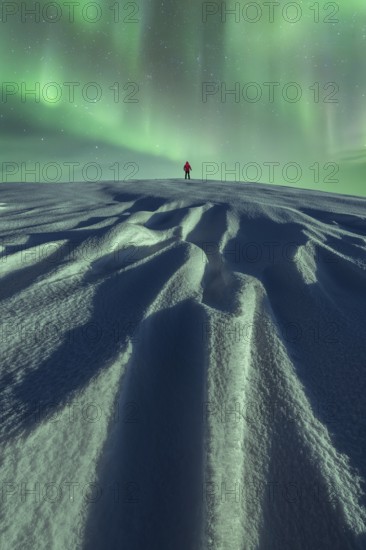 Unrecognizable person stands alone under the mesmerizing Aurora Borealis on a snowy landscape during a serene winter northern night