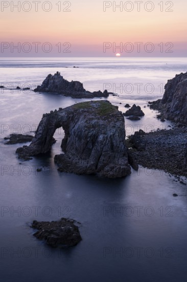Coastal landscape at Land's End. The Enys Dodnan Arch with rock gate. In the evening at sunset. Long exposure. Land's End, Penzance, Cornwall, England, Great Britain