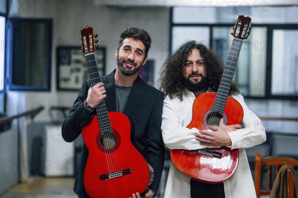 Portrait of confident male artists carrying red bass guitars in music studio
