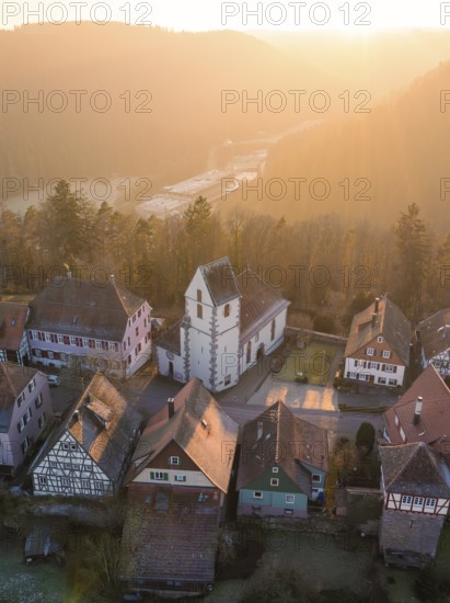 Half-timbered houses and a church in warm sunset light look idyllic and peaceful, Zavelstein, Calw district, Black Forest, Germany