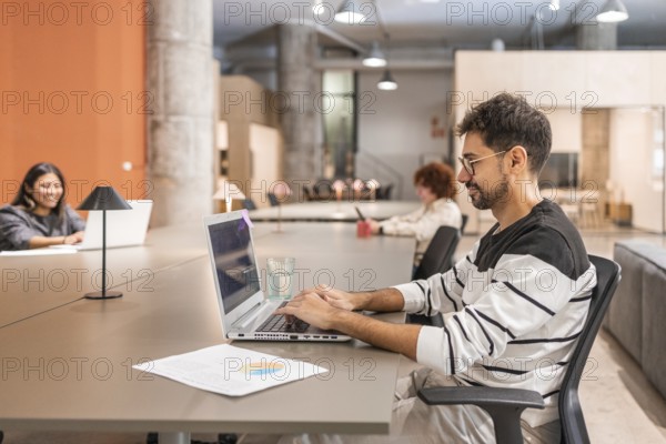 Diverse coworkers engaged in teamwork at a contemporary open space office Individuals working independently on laptops, fostering creativity and productivity in a collaborative environment