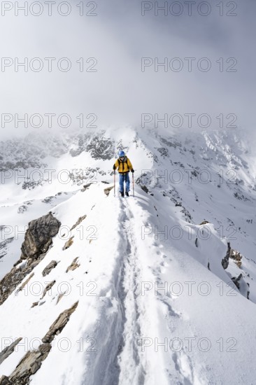 Mountaineer climbing up the narrow ridge of Piz Laviner, view of wintry mountain landscape, Grisons Haute Route, Albula Alps, Rhaetian Alps, Grisons, Eastern Switzerland, Switzerland