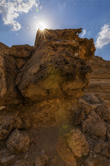 The morning sun shines over a reddened rock, Huqf stone desert, Arabian Peninsula, Sultanate of Oman