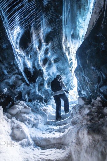 A person is walking through a cave with blue walls. The cave is very cold and the person is wearing a jacket