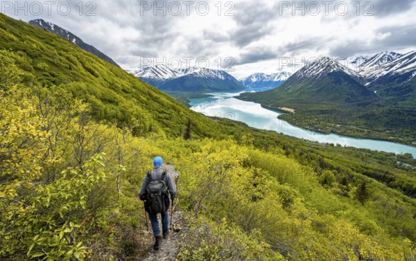 Climbers on a hiking trail, Slaughter Ridge Trail, view of snowy mountains in spring and turquoise blue Kenai Lake Lake, Cooper Landing, Kenai Peninsula, Alaska, USA