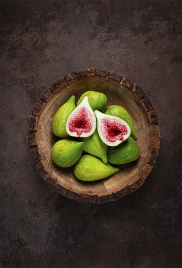 Fresh green figs, in a wooden plate, top view, close-up, no people