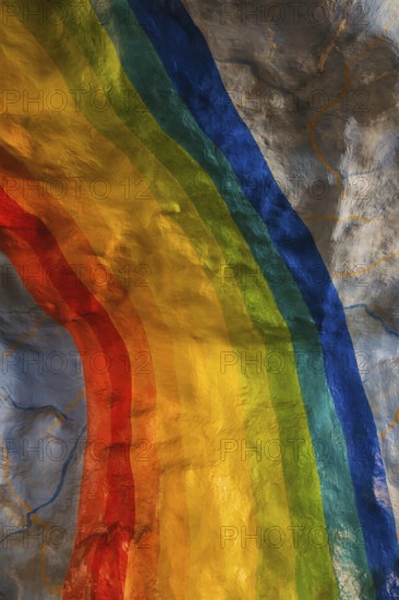 A colorful rainbow mural painted on a textured wall in Stockholm. The vivid hues contrast with the rugged surface, creating an artistic and inspiring urban scene celebrating diversity and hope