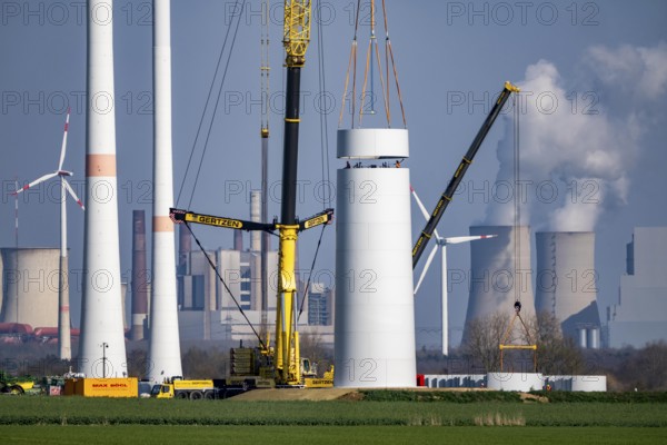 Construction site of the new Bedburg 3 wind farm, on recultivated open-cast mining site, 9 wind power plants with an output of 60 megawatts are newly built, installation of the wind turbine tower, in the background the Neurath lignite power plant, operated by RWE and the city of Bedburg, North Rhine-Westphalia, Germany
