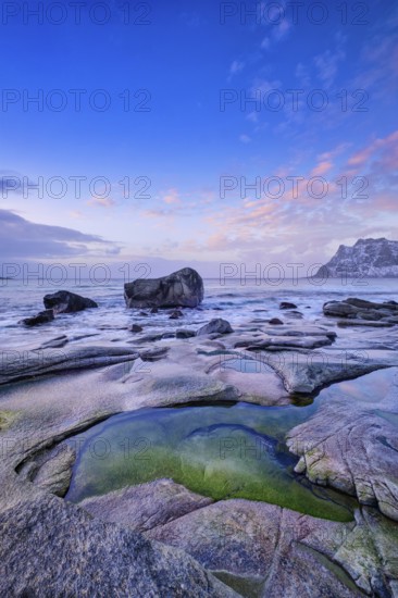 Rocks on beach of fjord of Norwegian sea in winteron sunset. Utakliev beach, Lofoten islands, Norway