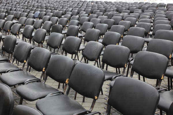 Chairs covered with gray plastic stand in rows in a function room, empty, vacant, seating