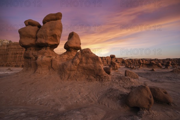 Dramatic sandstone formations under a vibrant sunset sky at Goblin Valley State Park, Utah. Captures the unique erosion and stunning colors of this natural landscape