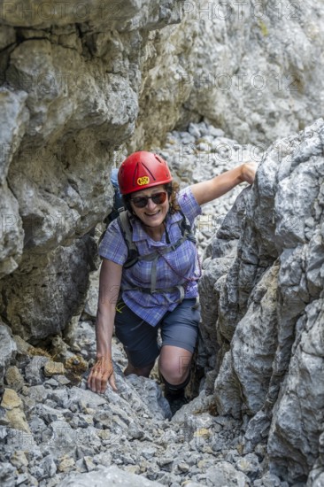 Female mountaineer with helmet climbing a rock face, ascent to the Ackerlspitze, Wilder Kaiser, Kaiser Mountains, Tyrol, Austria