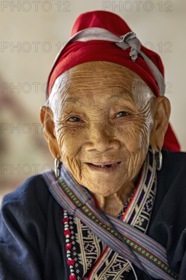 Portrait of an elderly woman with a traditional headscarf and smiling face, large Buddha statue at Fansipan in the mountains near Sa Pa in Vietnam