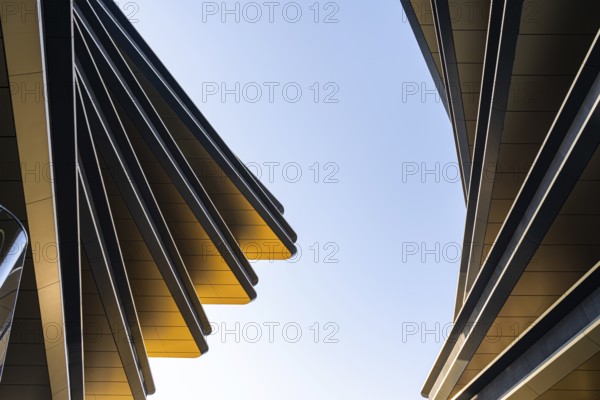 This image showcases the dynamic lines and sleek surfaces of modern architecture against a clear blue sky, highlighting innovative design and urban aesthetics
