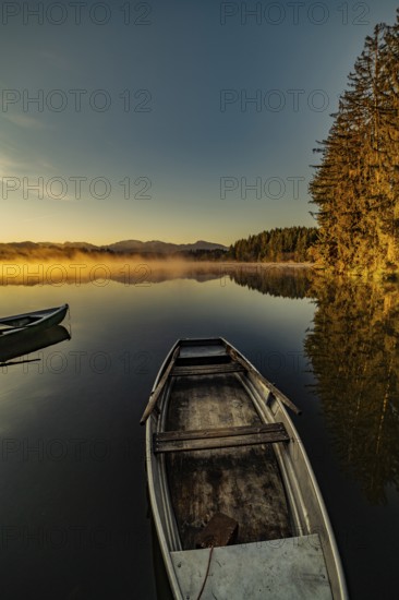 Boats in the autumnal Schmutter Weiher in the Allgäu near the municipalities of Halblech, Roßhaupten and Lechbruck in Ostallgäu in the foothills of the Alps