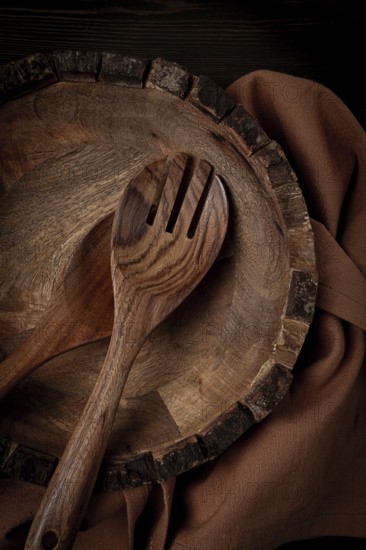 Wooden plate, handmade, with salad spoons, top view, on a wooden table, no people