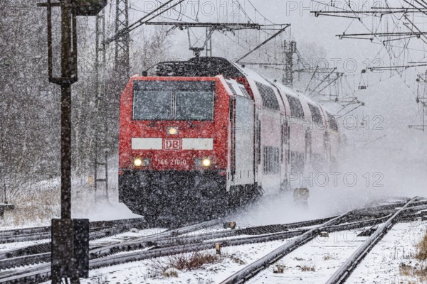 RegionalExpress RE on the road through a winter landscape in snowfall. A train on the line in the Deutsche Bahn AG rail network. Amstetten, Baden-Württemberg, Germany