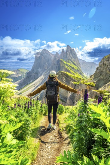 Hiker walking along a path with open arms, enjoying the view of the odle mountains in the italian dolomites during summer