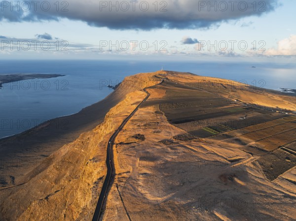 Road on cliffs in evening light, steep cliffs on the coast near Mirador del Porrito, aerial view, at sunset, Lanzarote, Canary Islands, Spain