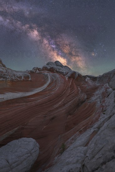Stunning nightscape of White Pocket in Arizona, USA, with the Milky Way galaxy beautifully illuminating the sky above unique desert rock formations and swirling patterns