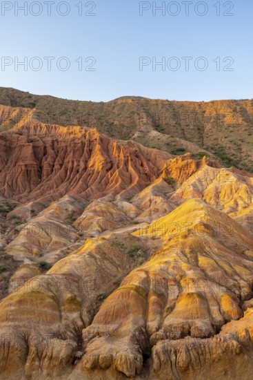 Erosion landscape of red and yellow sandstone, rock formations at sunrise, Skazka Canyon, fairytale gorge, Tosor, Kyrgyzstan