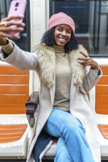 Cheerful young woman takes a selfie on public transport, making peace sign with fingers while smiling