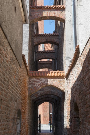 A narrow, arched passageway made of bricks with historical flair, 13th century church path, Elblag, Elbing, Warminsko-Mazurskie Voivodeship, Warminsko-Mazurskie, Poland