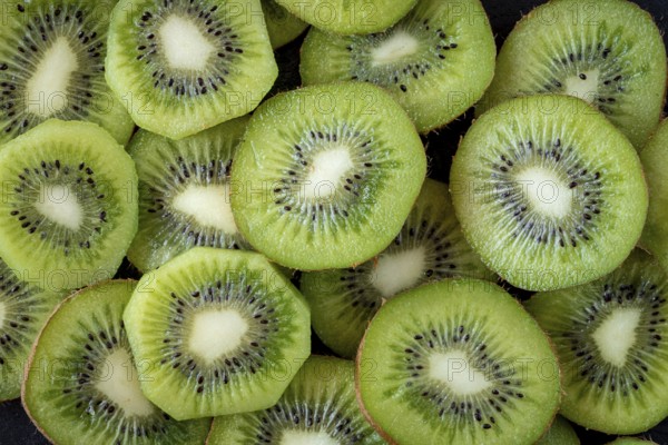 A close up view of multiple fresh kiwi slices revealing their vibrant green color and distinctive seed pattern, highlighting their juicy and refreshing texture