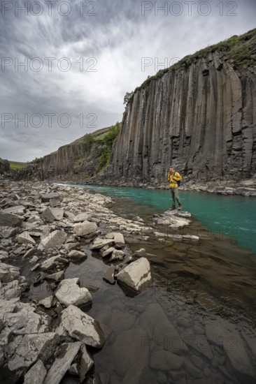Tourist standing by the river in Stuðlagil Canyon, turquoise blue river between basalt columns, Egilsstadir, Iceland