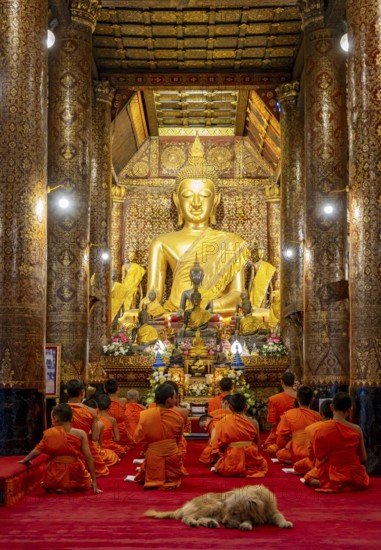 Buddhist monks praying at Wat Xieng Thong Sim ordination hall, Luang Prabang, Laos