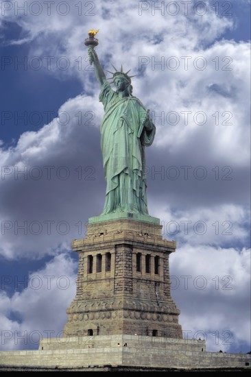 Statue of Liberty in front of New York, cloudy sky, USA