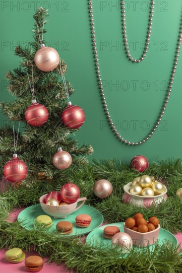 Small Christmas tree with baubles and macaroons in pink and green, surrounded by decorations