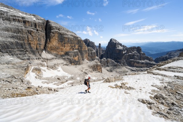 Mountaineers in a snowfield on the Sella della Tosa, mountain landscape with steep cliffs, Brenta Mountains, Brenta-Adamello Natural Park, Trentino, Italy