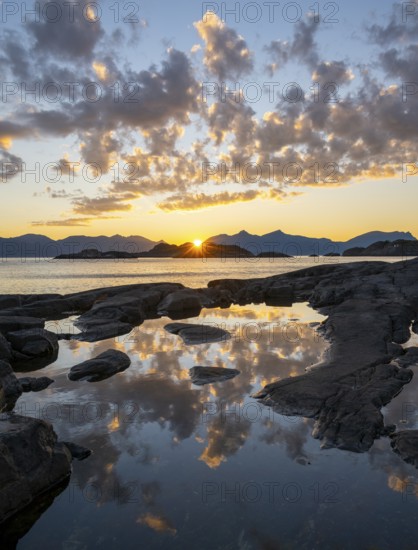 Clouds reflected in a small pond on a rocky coast, coastal landscape at sunset, Henningsvær, Lofoten, Nordland, Norway
