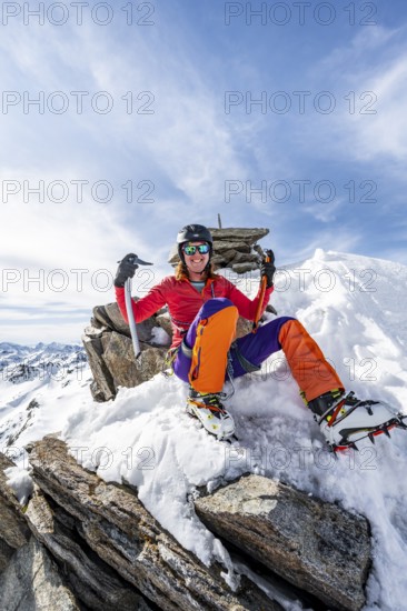 Happy mountaineer with ice axes and crampons on the summit of Piz Grialetsch in winter, Graubünden Haute Route, Albula Alps, Rhaetian Alps, Graubünden, Switzerland