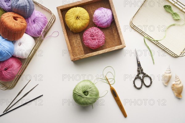 Top view of various colored yarns, crochet hooks, and ornate scissors arranged for needlework and jewelry creation. Perfect for showcasing handcrafted artistry