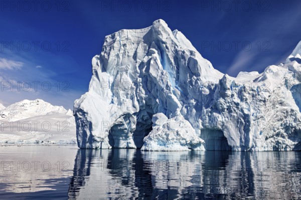 Imposing icebergs are reflected in the calm water under a clear blue sky, icebergs in the Southern Ocean in Antarctica
