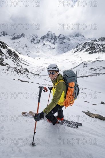 Skier skiing down a steep slope, Piz Laviner, view of mountain panorama in wintry mountain landscape with dramatic clouds, Grisons Haute Route, Albula Alps, Rhaetian Alps, Grisons, Eastern Switzerland, Switzerland